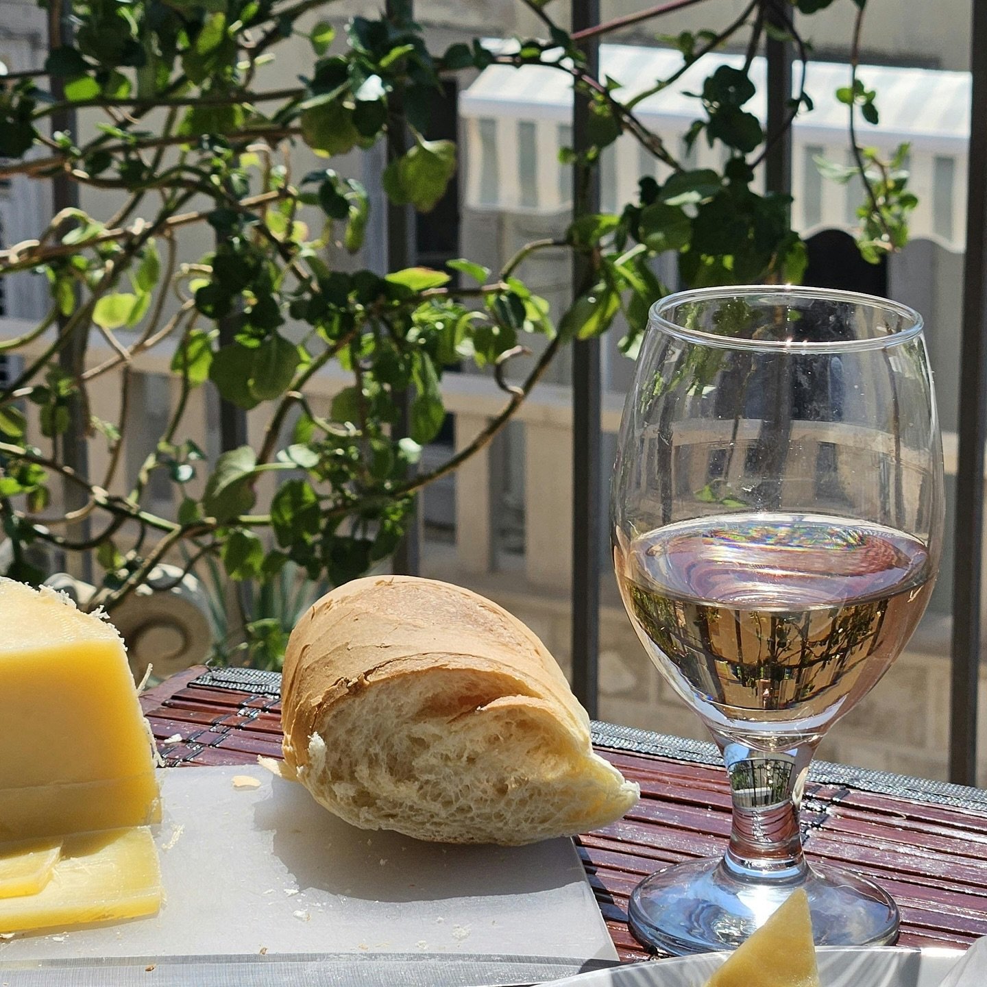 Outdoor dining with wine glass in sunlit Mediterranean setting